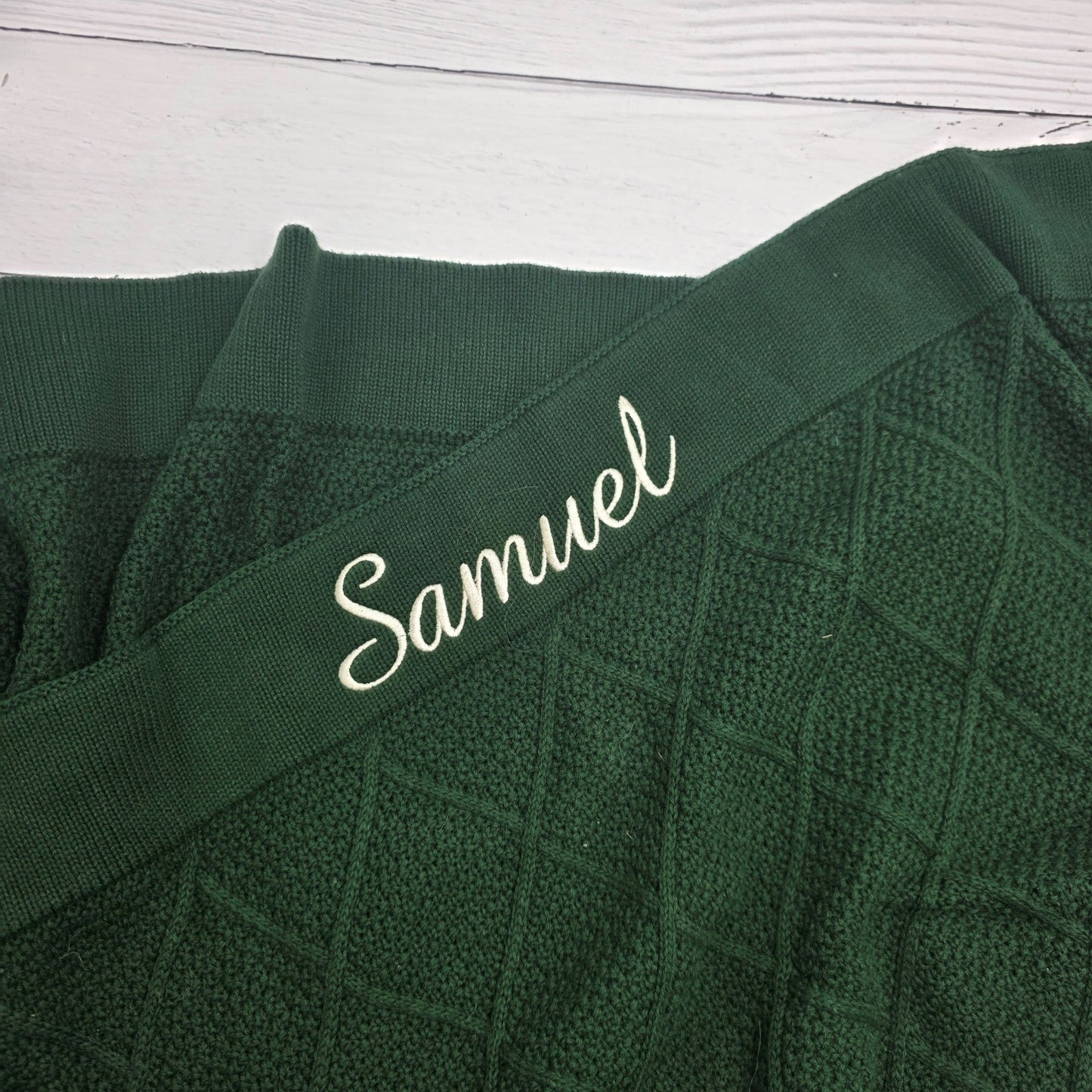 Green fabric with 'Samuel' embroidered on a white wooden surface
