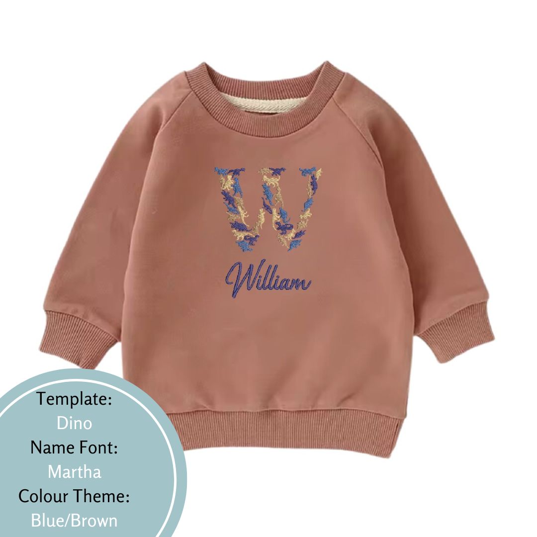 latte brown baby and toddler crewneck jumper embroidered with a dunosaur name design using a blue and brown colour theme