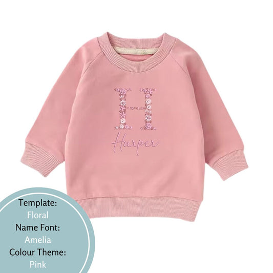 pink baby and toddler crewneck jumper embroidered with a floral name design using a pink colour theme