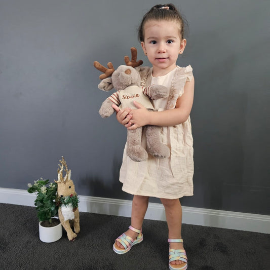 Girl holding Soft Brown reindeer wearing a knit jumper personalised with name embroidery