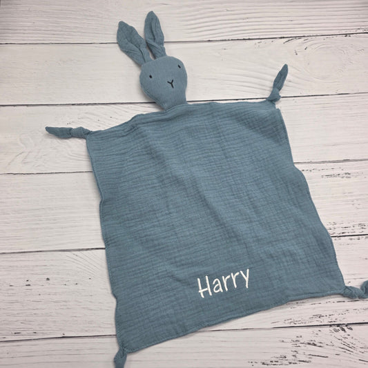 Blue textured blanket with a bunny toy and 'Harry' embroidered on a wooden surface