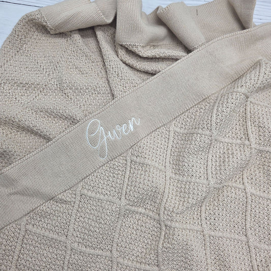Close-up of a textured beige fabric with the name 'Gwen' embroidered on it.