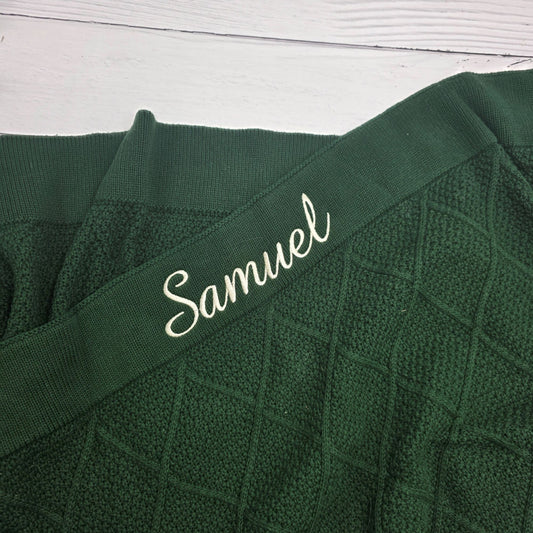 Green fabric with 'Samuel' embroidered on a white wooden surface