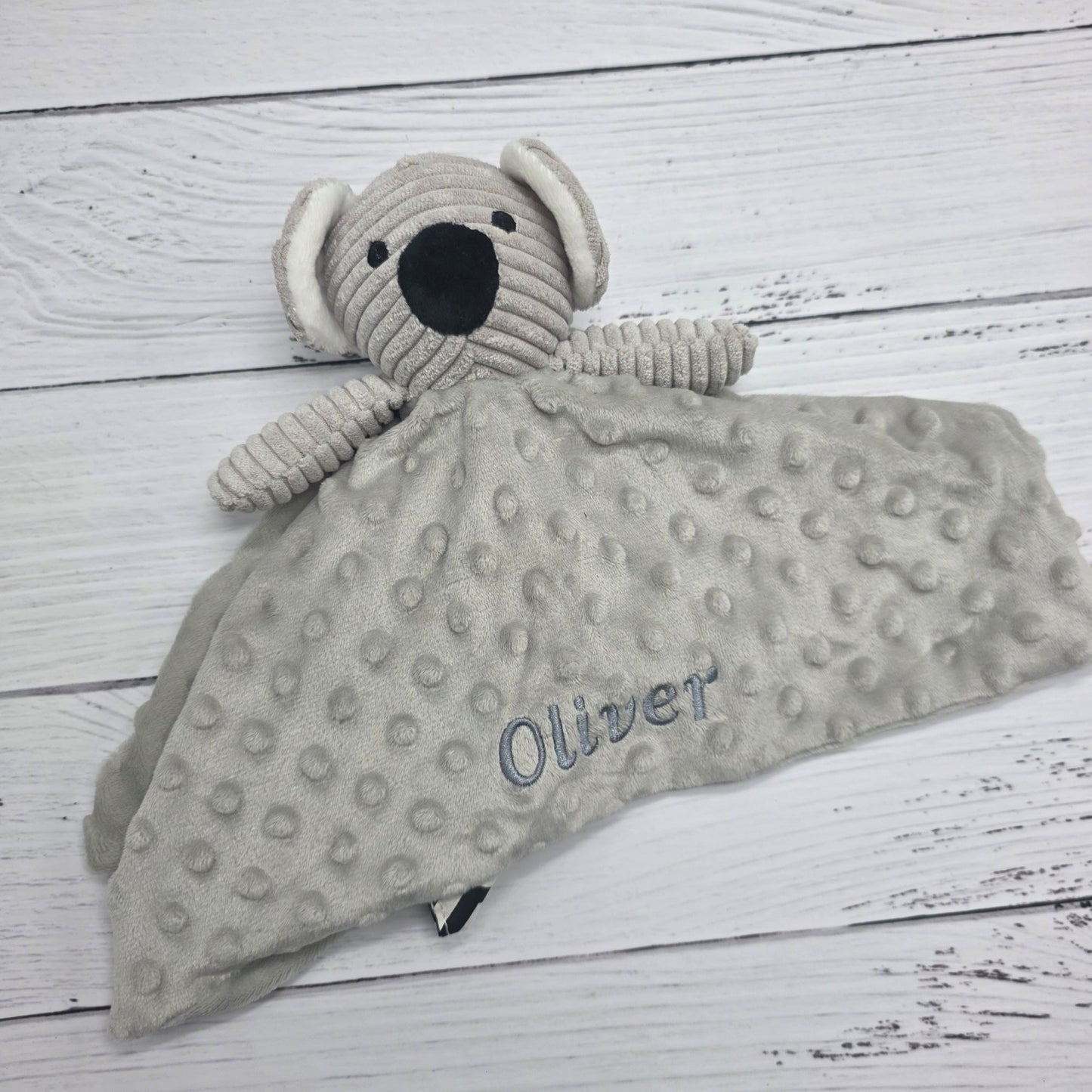 Gray textured comfort blanket with a dog toy on a wooden surface