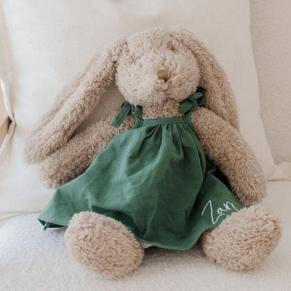 Plush bunny toy with a green dress on a white couch
