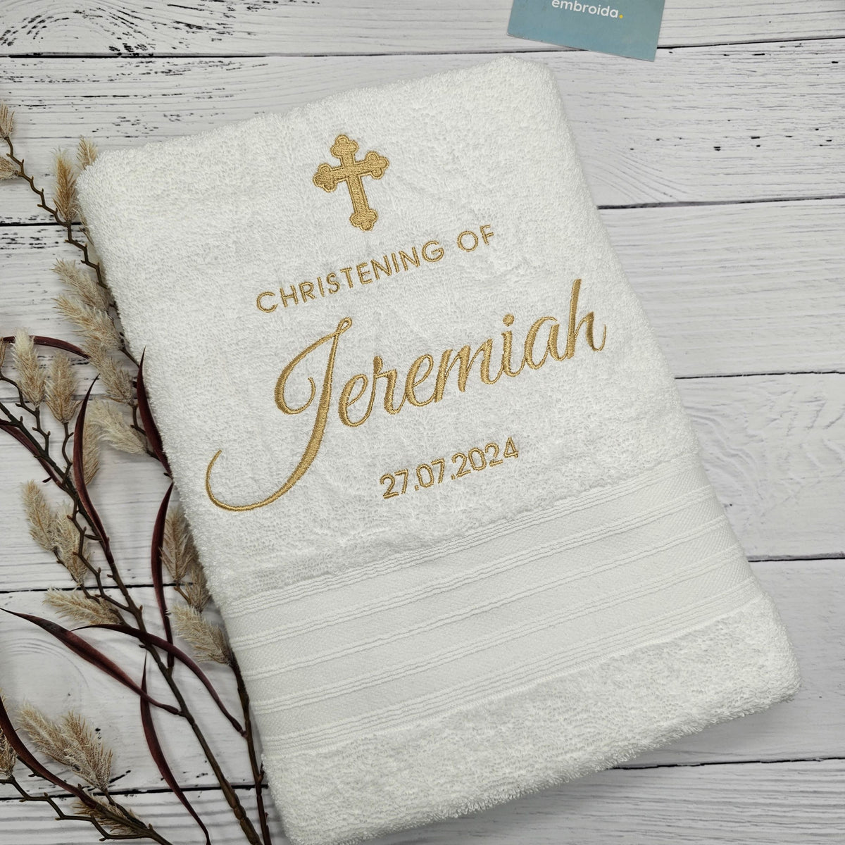 Personalized Christening towel with embroidered name and date on a wooden surface