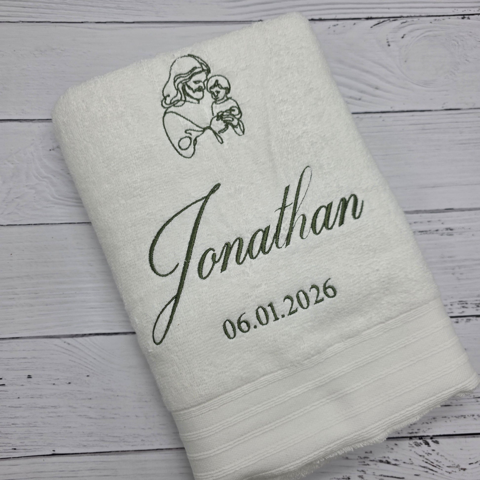 Personalized Christening towel with embroidered name and date on a wooden surface