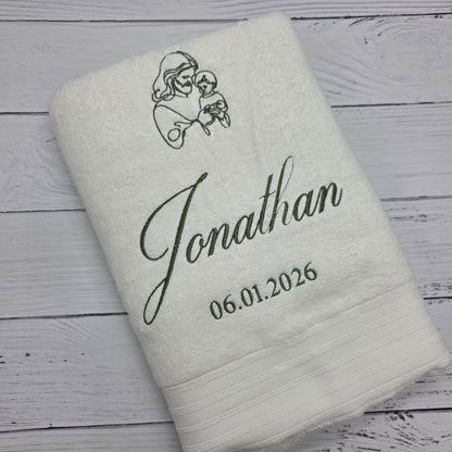 Personalized Christening towel with embroidered name and date on a wooden surface