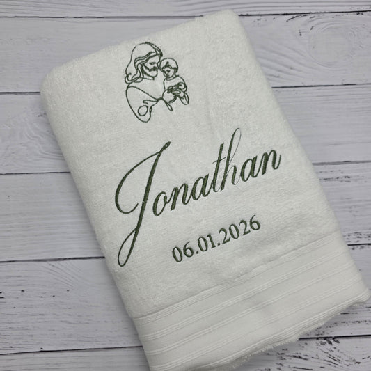 Personalized Christening towel with embroidered name and date on a wooden surface