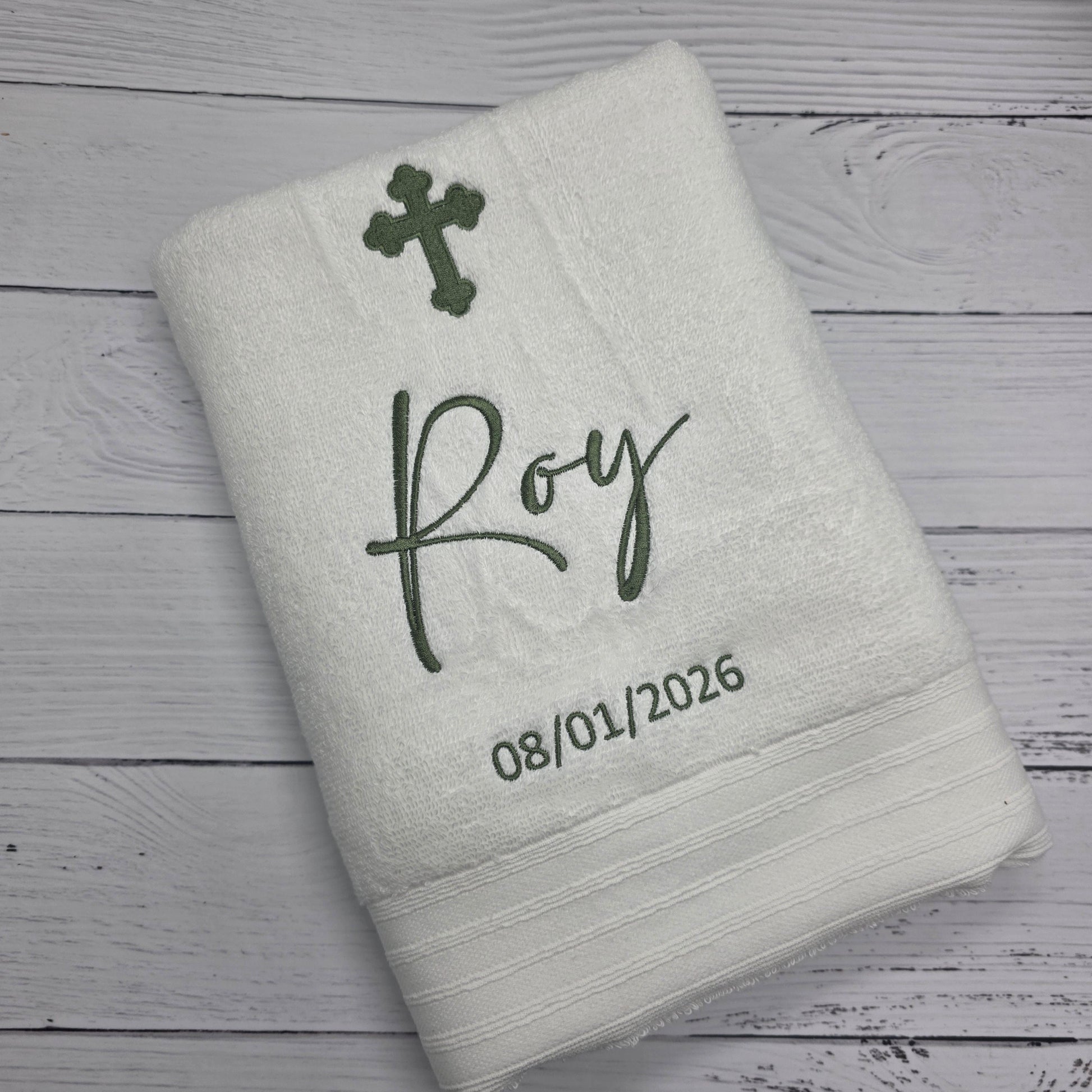 Gray towel with embroidered text and design on a wooden surface