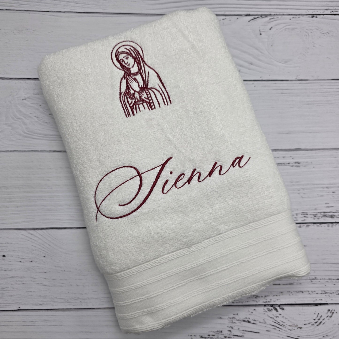 White towel with embroidered design and text on a wooden surface