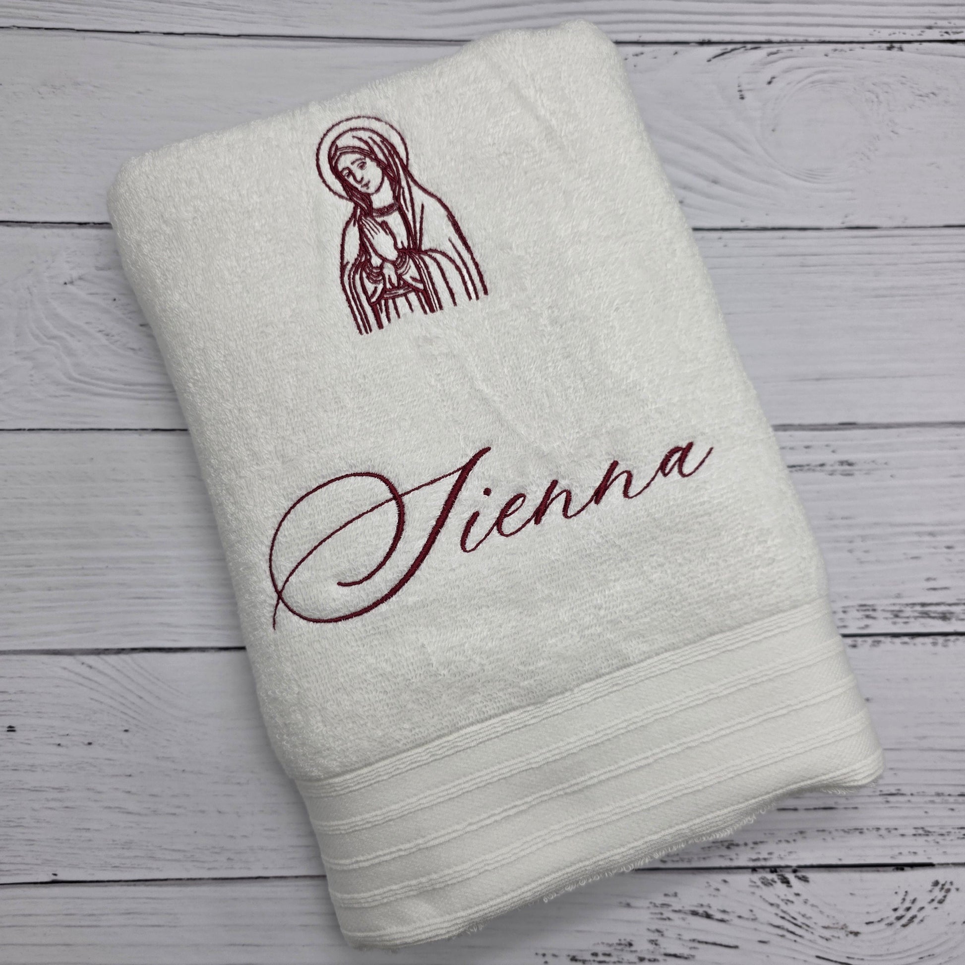 White towel with embroidered design and text on a wooden surface