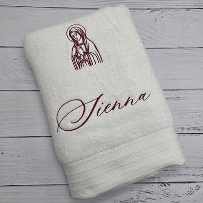White towel with embroidered design and text on a wooden surface