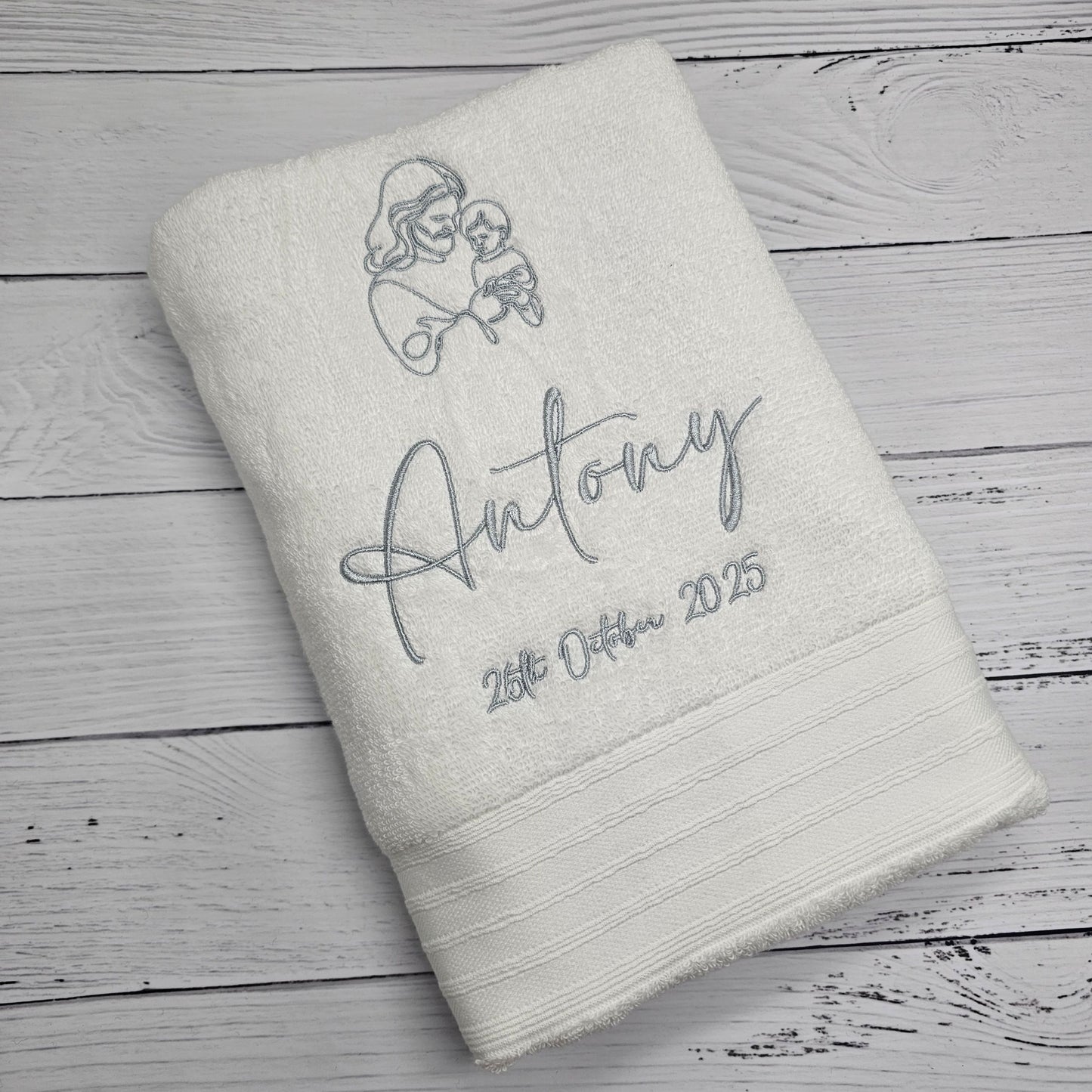 White towel with personalized embroidery on a wooden surface