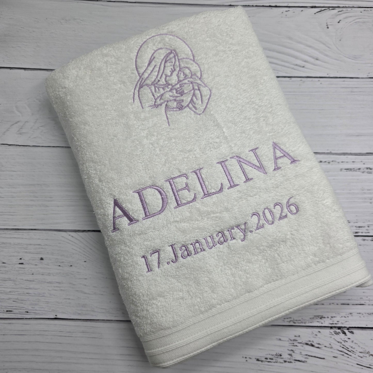 Light gray towel with embroidered text and design on a wooden surface