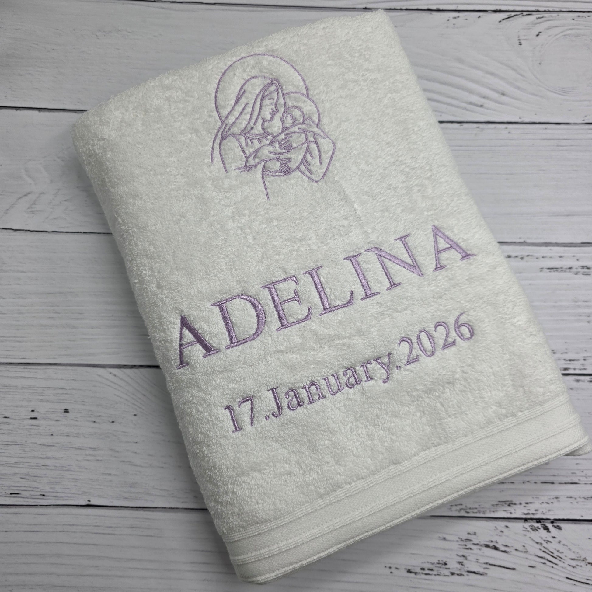 Light gray towel with embroidered text and design on a wooden surface