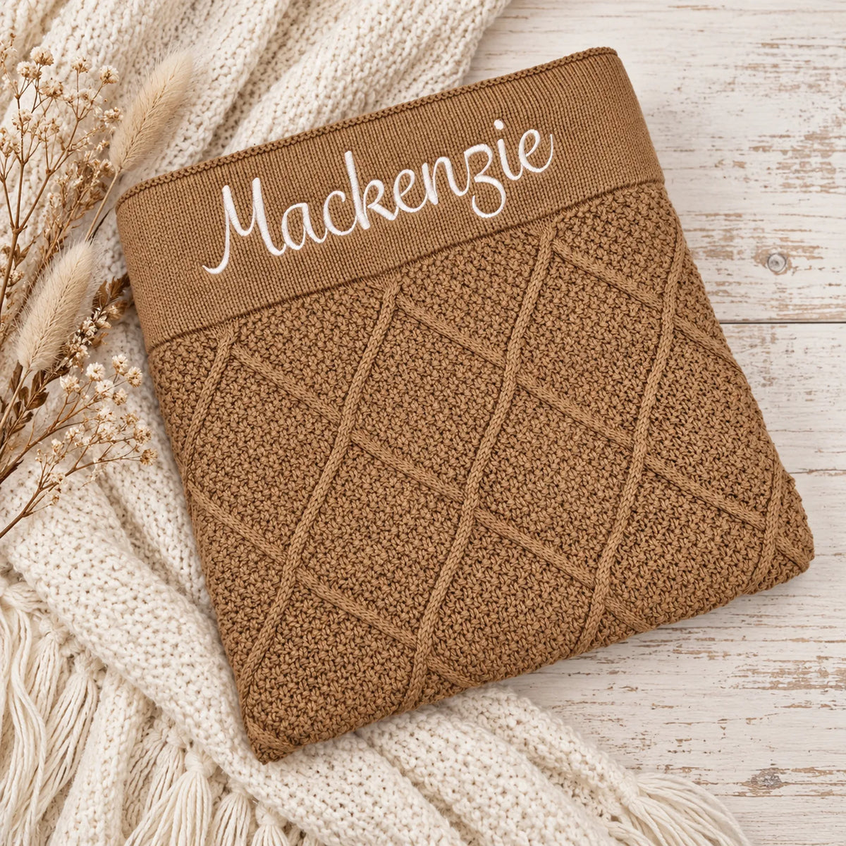 A tan brown diamond knit blankets embroidered with the name Mackenzie