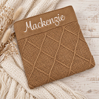 A tan brown diamond knit blankets embroidered with the name Mackenzie